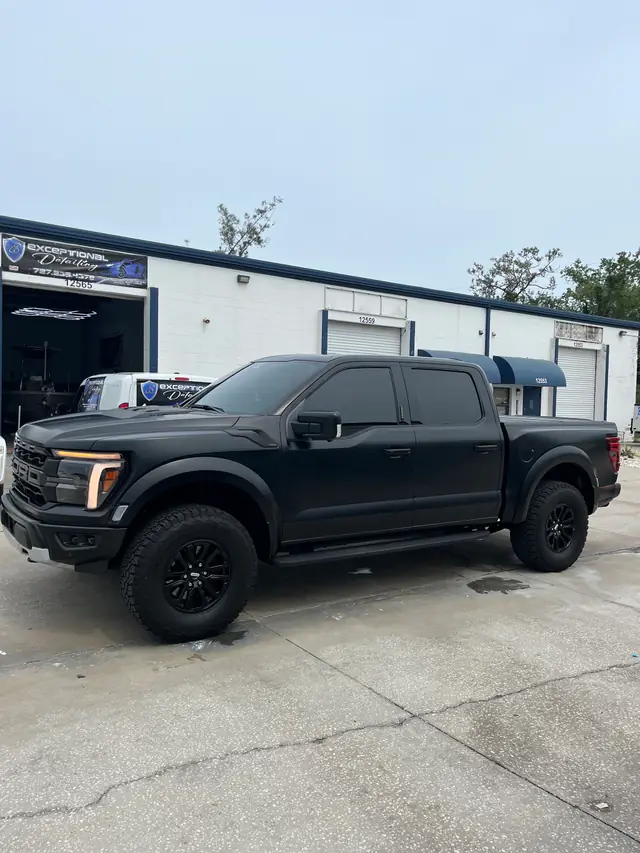 Matte-black Ford F-150 Raptor outside the shop