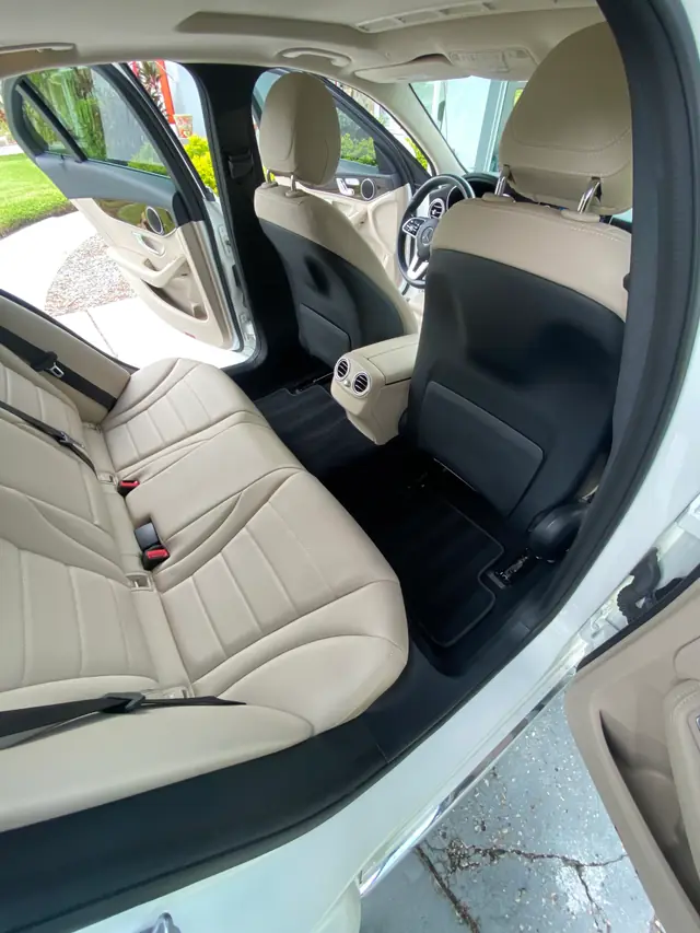 Cream leather rear seats and clean black floor mats in a Mercedes cabin
