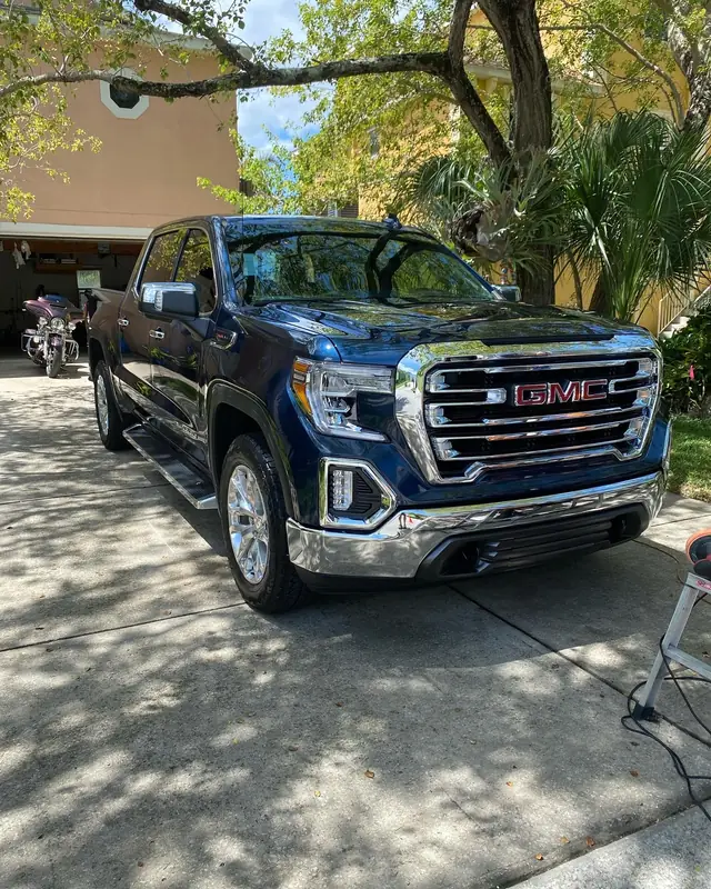 Dark blue GMC Sierra with a deep, even gloss parked in the shade