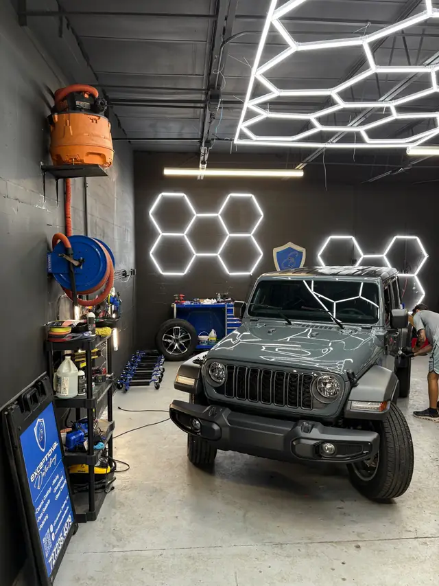 Grey Jeep Wrangler in the bay with the hex lights reflected across its hood